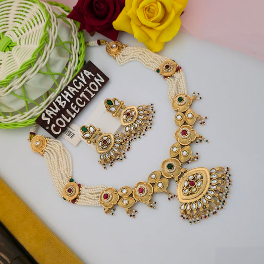 antique gold tone kundan style necklace set, traditional maroon green stone necklace with matching earrings, ivory pearl bead necklace for women, leaf shaped pendant necklace with white teardrop stones, antique finish artificial jewellery set, traditional Indian necklace with hanging bead details, ethnic wedding necklace set for women, maroon green gold tone necklace with matching earrings