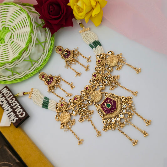 antique gold tone maroon green stone necklace set, traditional artificial necklace with geometric maroon pendant, ivory bead necklace with green accents, antique gold necklace with long decorative chain tassels, maroon enamel ethnic necklace set with matching earrings, traditional Indian jewellery with white stone embellishments, statement necklace set for wedding and festive wear