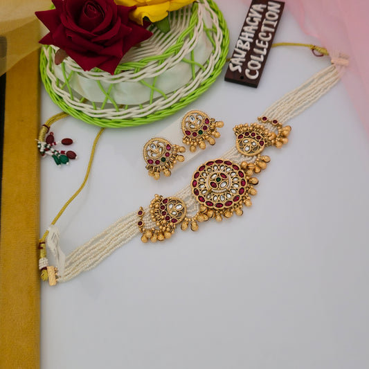 antique gold tone white bead necklace set, traditional necklace with red green and white stones, multi strand white bead artificial jewellery, circular statement pendant necklace for women, antique gold necklace with matching earrings, traditional ethnic jewellery with golden bead hangings, red stone festive necklace set, white bead necklace with antique gold detailing