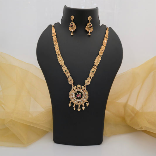 gold plated Rajwadi polish necklace set, traditional long necklace with circular floral pendant, antique gold tone necklace with matching earrings, green and maroon stone artificial jewellery, designer Rajwadi necklace for women, traditional Indian wedding jewellery, festive long necklace set, floral pendant necklace with drop earrings