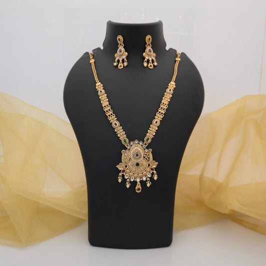 gold plated Rajwadi polish necklace set, traditional long necklace with ornate pendant, antique gold tone designer necklace for women, Rajwadi necklace with green and maroon stone accents, traditional necklace set with matching earrings, Indian wedding jewellery, festive ethnic necklace, artificial jewellery for women