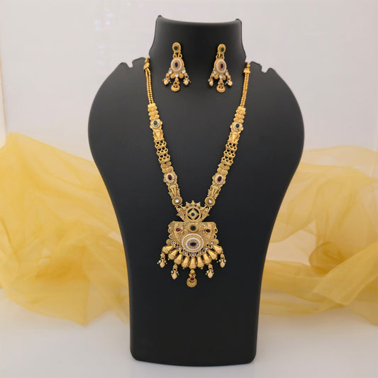 gold plated Rajwadi polish necklace set, traditional long necklace with ornate pendant, designer artificial jewellery for women, antique gold tone necklace with green and maroon stones, Rajwadi necklace with matching earrings, traditional Indian wedding jewellery, festive long pendant necklace set, ethnic jewellery for women