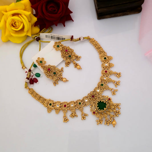 Gold plated Rajwadi polish short necklace set featuring a deep green teardrop pendant, multicolour floral motifs, red green and white decorative stones, intricate gold-tone detailing and matching traditional earrings