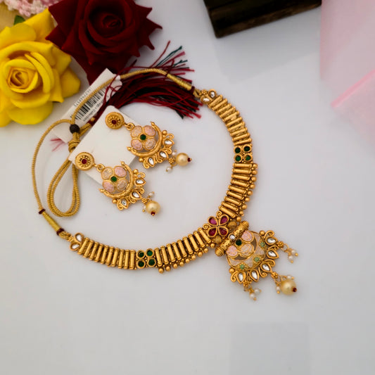 Gold plated Rajwadi polish short necklace set featuring a ribbed gold-tone design, pink and green floral enamel motifs, white teardrop stones, decorative pendant and matching earrings with pearl-like drops