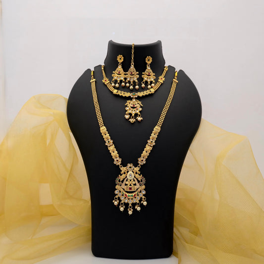old plated short and long necklace combo set featuring a peacock-inspired statement pendant, intricate floral motifs, red green and white decorative stones, pearl-drop embellishments, matching earrings and maang tikka displayed on a black jewellery bust