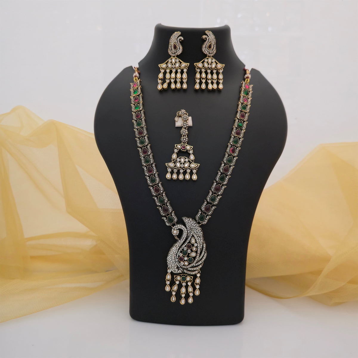 multicolour Moissanite and AD necklace set with matching earrings and maang tikka, green and maroon stone necklace for women, peacock-inspired designer pendant necklace, antique gold-tone traditional jewellery set, white stone statement necklace with colourful accents, ethnic wedding jewellery for women, matching earrings and maang tikka set, Scofjewel multicolour necklace