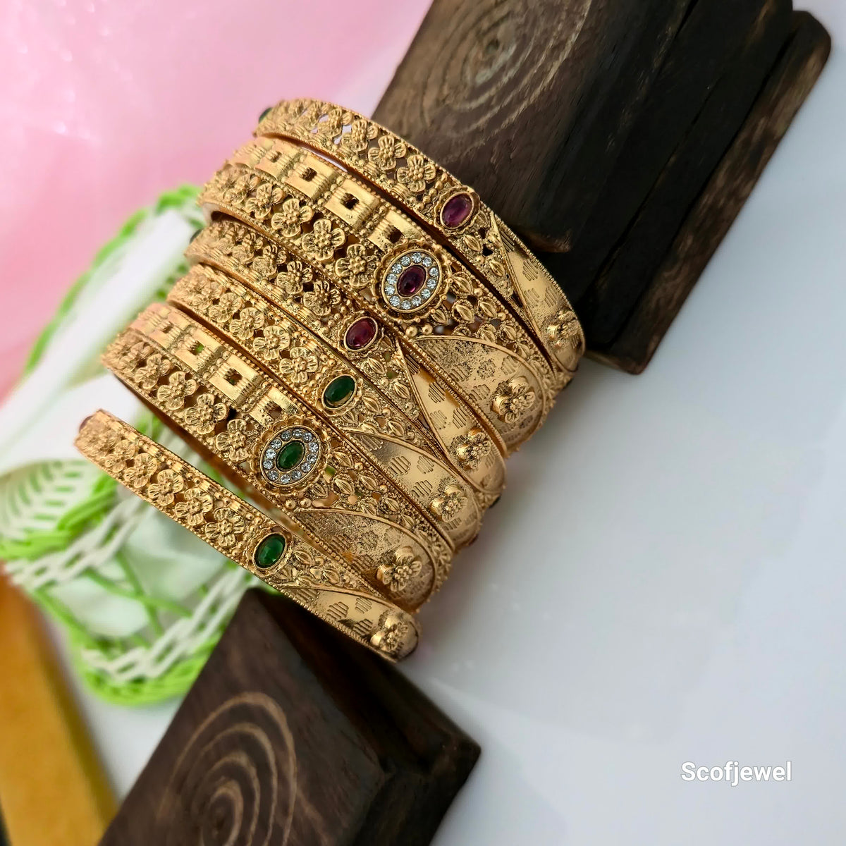 Rajwadi polish antique gold bangles with intricate floral embossing, traditional designer bangles with red and green stone accents, ornate gold tone bangles for women, floral engraved Rajwadi bangles, traditional Indian wedding bangles, antique finish ethnic jewellery, decorative stone bangles for festive wear, Scofjewel Rajwadi bangles