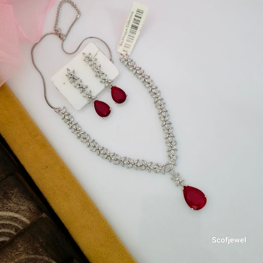 red stone designer necklace set with matching earrings, red teardrop pendant necklace for women, silver tone floral necklace with red stones, red drop earrings with white floral stone detailing, elegant red party wear necklace set, traditional red necklace set for weddings, artificial jewellery with red teardrop stones, silver floral necklace with matching earrings, Scofjewel red stone necklace set