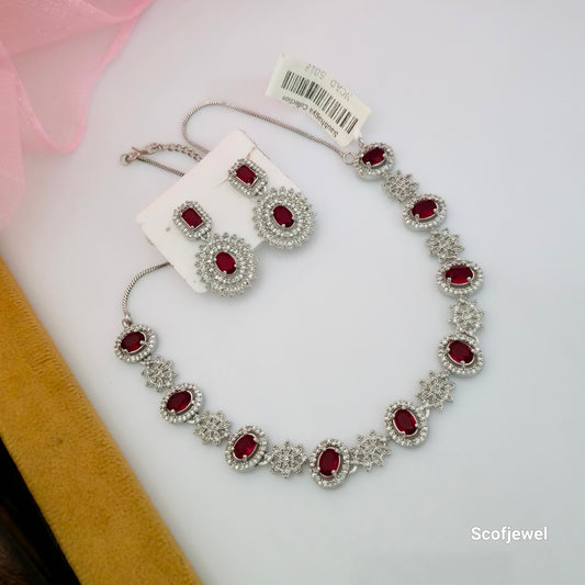ruby red American Diamond necklace set with matching earrings, red oval stone necklace for women, silver tone designer necklace with white sparkling accents, floral motif red stone necklace set, artificial jewellery necklace with matching statement earrings, elegant red necklace for wedding and festive wear, Scofjewel red stone necklace set