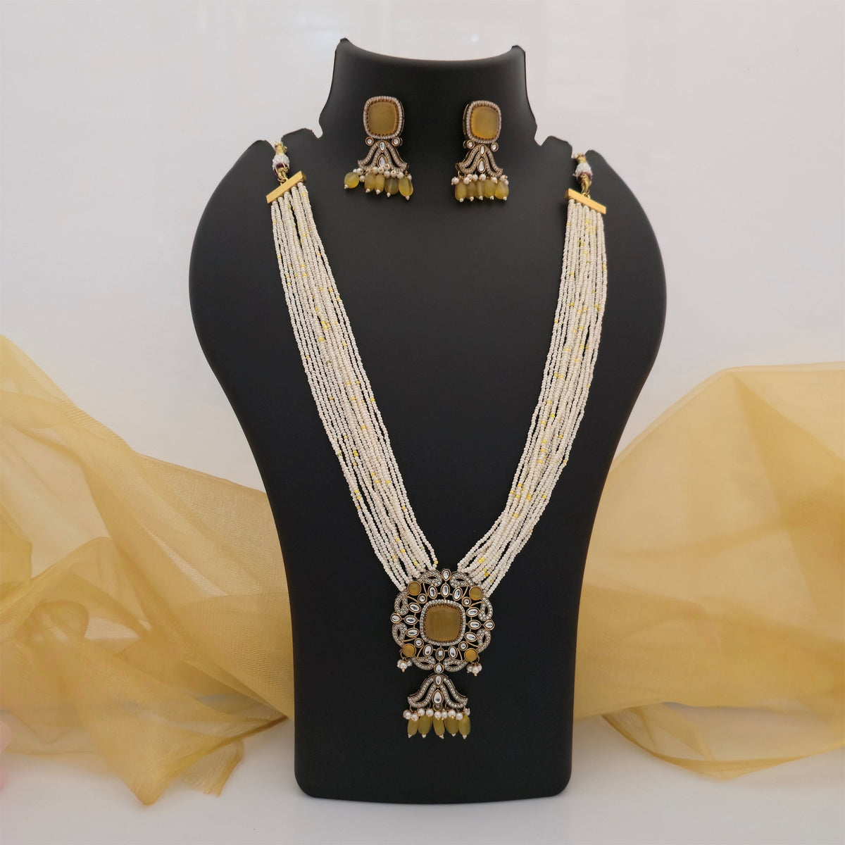 white beaded Moissanite Kundan long necklace set with yellow pendant, multi strand white bead necklace with yellow accents, traditional gold tone necklace with floral centre pendant, white and yellow Kundan-style necklace for women, long ethnic beaded necklace for weddings, designer Indian imitation jewellery with yellow stones, statement necklace with dangling yellow details, Scofjewel long beaded necklace set